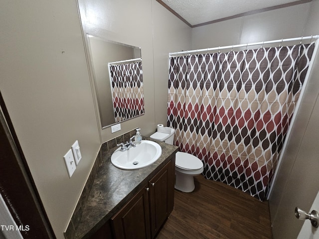 bathroom with toilet, a textured ceiling, ornamental molding, vanity, and hardwood / wood-style flooring