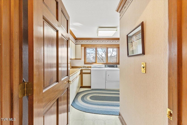 washroom with sink, washer and clothes dryer, and ornamental molding