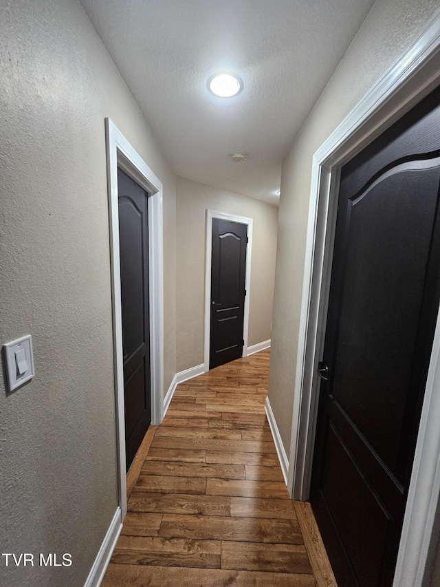 hall with hardwood / wood-style floors and a textured ceiling