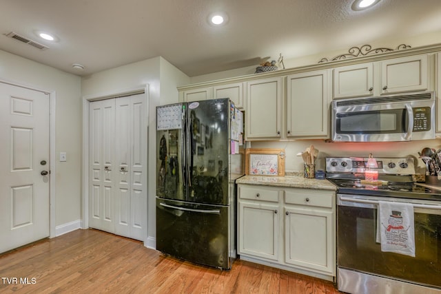 kitchen with appliances with stainless steel finishes, light hardwood / wood-style floors, and cream cabinets