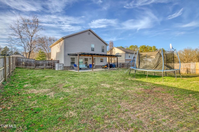 back of property with a trampoline, a yard, and a patio area