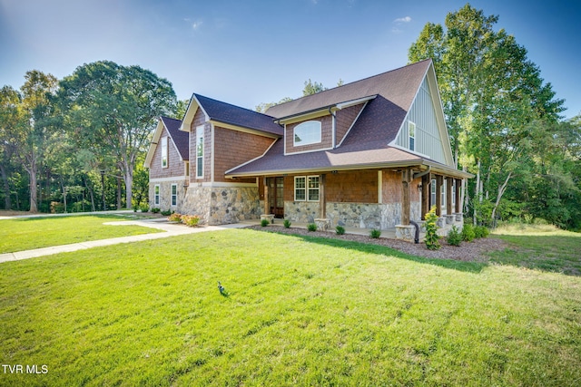 view of front of home featuring a front yard, stone siding, and roof with shingles