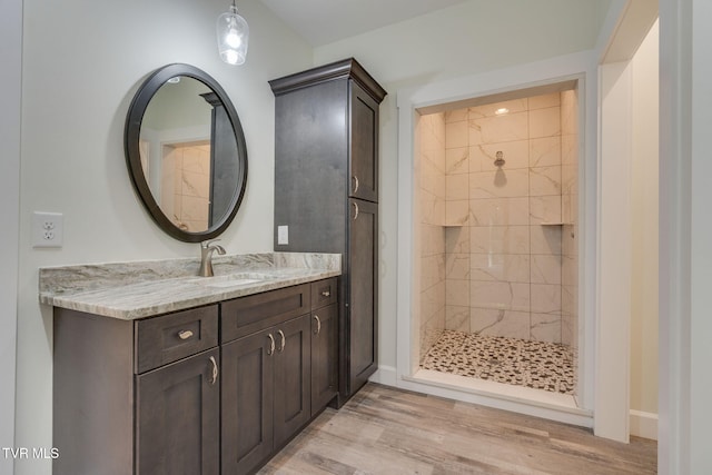 bathroom featuring a stall shower, baseboards, wood finished floors, and vanity