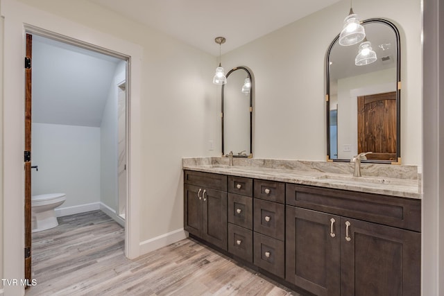 full bath with double vanity, wood finished floors, a sink, and baseboards