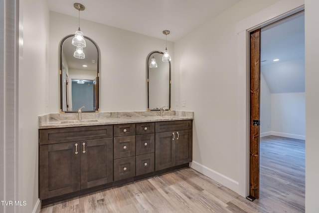 bathroom featuring double vanity, baseboards, a sink, and wood finished floors