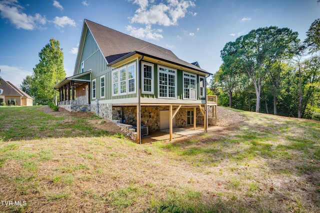 back of property with a garage, stone siding, a yard, driveway, and board and batten siding