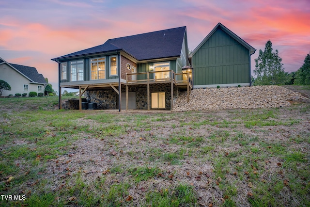 back of property with stone siding, board and batten siding, and a wooden deck