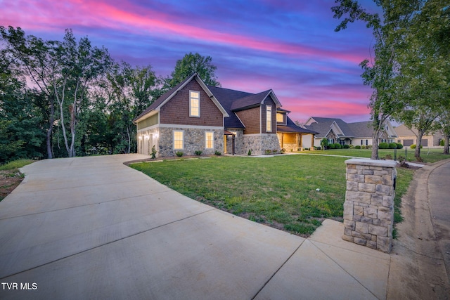 view of front of house with a garage, concrete driveway, stone siding, and a front yard