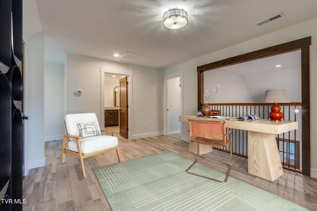 living area with stacked washer / dryer, visible vents, baseboards, light wood-type flooring, and attic access