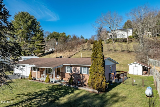 back of property featuring brick siding, a yard, covered porch, a storage shed, and fence