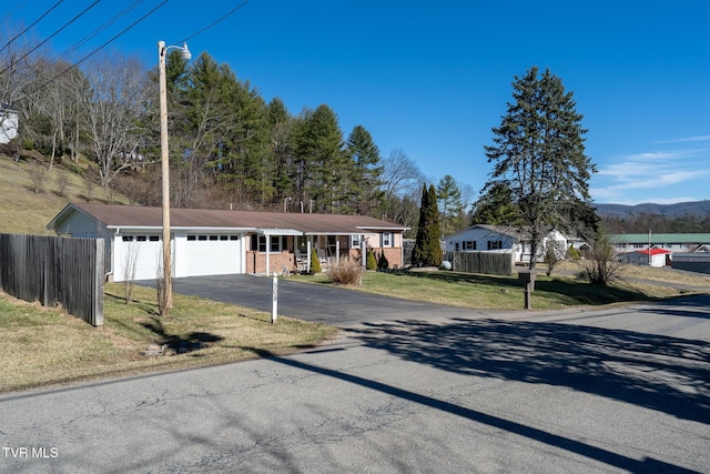 view of front facade featuring driveway, an attached garage, fence, a front lawn, and brick siding