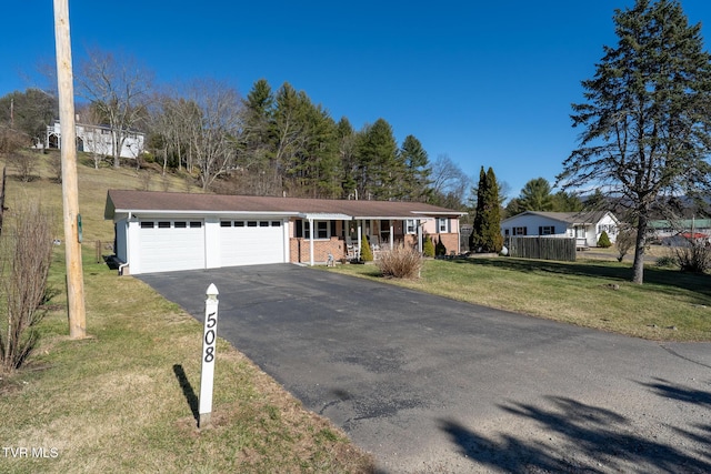 ranch-style home featuring aphalt driveway, brick siding, an attached garage, fence, and a front lawn