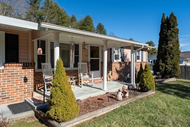 view of front of home featuring covered porch, brick siding, and a front lawn