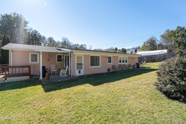 rear view of property with fence, a lawn, a deck, and a patio