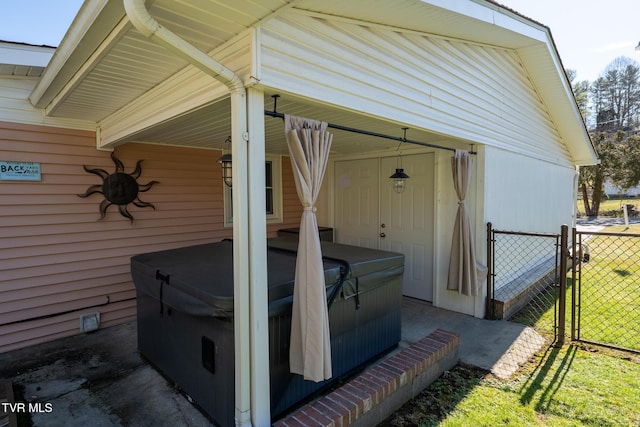 exterior space with a hot tub, a gate, and fence