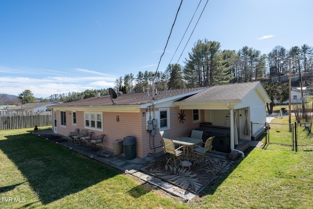 rear view of property featuring a gate, fence, a lawn, and a patio