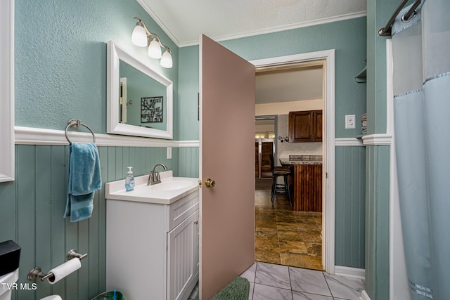 full bath with a wainscoted wall, vanity, and crown molding