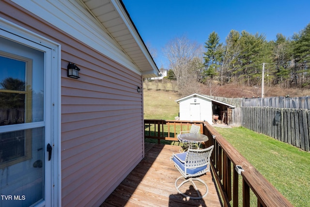 wooden terrace featuring a storage shed, a fenced backyard, a lawn, and an outdoor structure