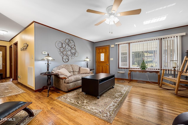 living area with baseboards, visible vents, ornamental molding, and wood finished floors