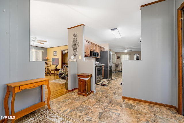 kitchen with stone finish flooring, baseboards, stainless steel appliances, and a ceiling fan