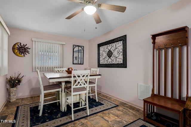 dining area with stone tile floors, visible vents, ceiling fan, and baseboards