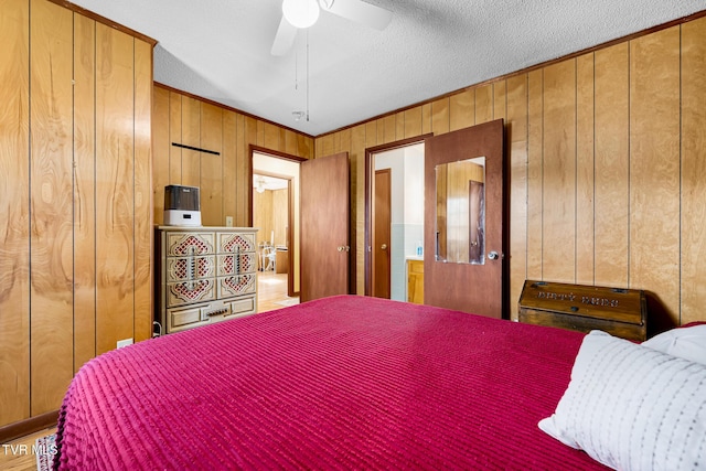 bedroom featuring ceiling fan, wooden walls, and a textured ceiling