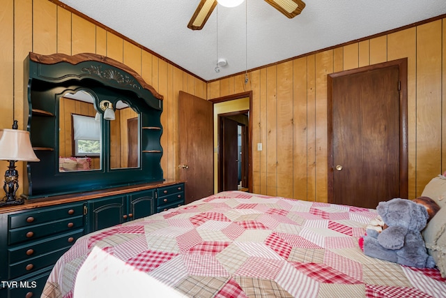 bedroom featuring ornamental molding, ceiling fan, wooden walls, and a textured ceiling