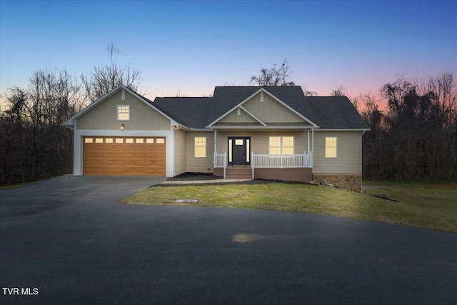 view of front of house featuring a garage, a lawn, and a porch