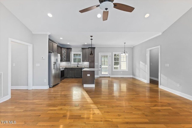 kitchen with a kitchen island, pendant lighting, sink, stainless steel fridge, and dark brown cabinets