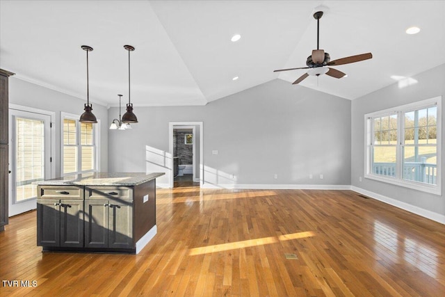 kitchen featuring hanging light fixtures, light stone countertops, a center island, and light wood-type flooring