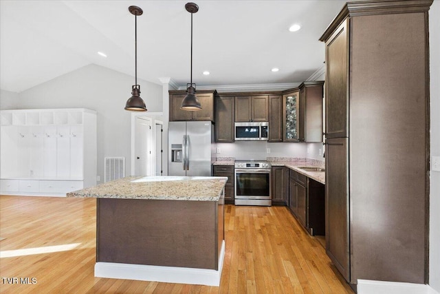 kitchen with a kitchen island, hanging light fixtures, dark brown cabinetry, light stone counters, and stainless steel appliances