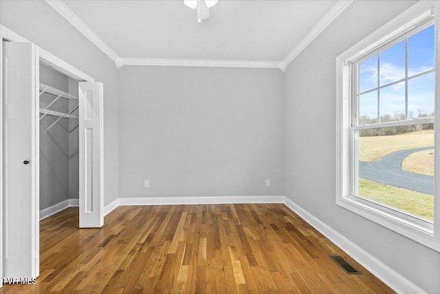 unfurnished bedroom featuring hardwood / wood-style floors, ornamental molding, and a closet