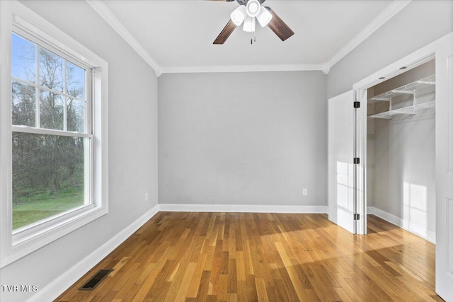 unfurnished bedroom featuring wood-type flooring, ornamental molding, a closet, and ceiling fan