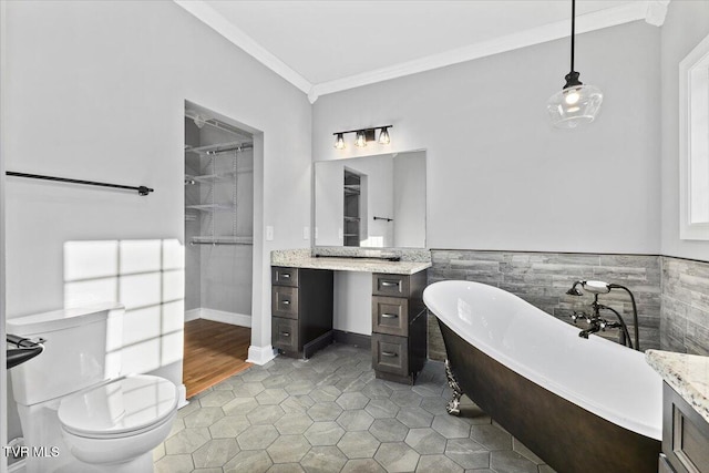 bathroom with tile patterned floors, a tub to relax in, toilet, ornamental molding, and vanity