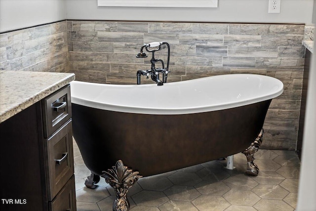 bathroom with tile patterned flooring, vanity, tile walls, and a tub to relax in