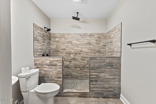 bathroom featuring a tile shower and toilet