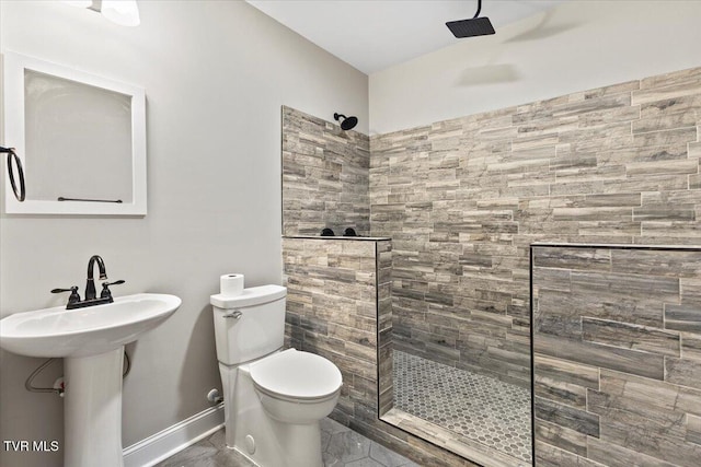 bathroom featuring sink, a tile shower, and toilet