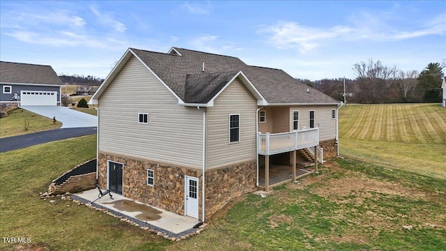 back of house with a garage, a wooden deck, and a lawn