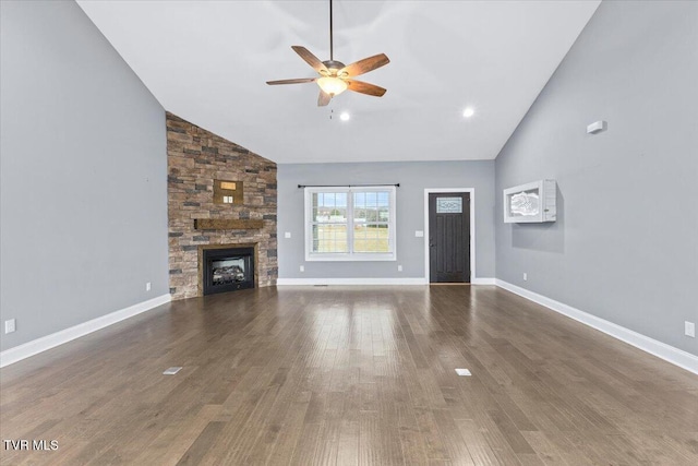 unfurnished living room featuring a stone fireplace, dark wood-type flooring, high vaulted ceiling, and ceiling fan