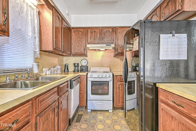 kitchen featuring black refrigerator, white electric stove, sink, stainless steel dishwasher, and a textured ceiling