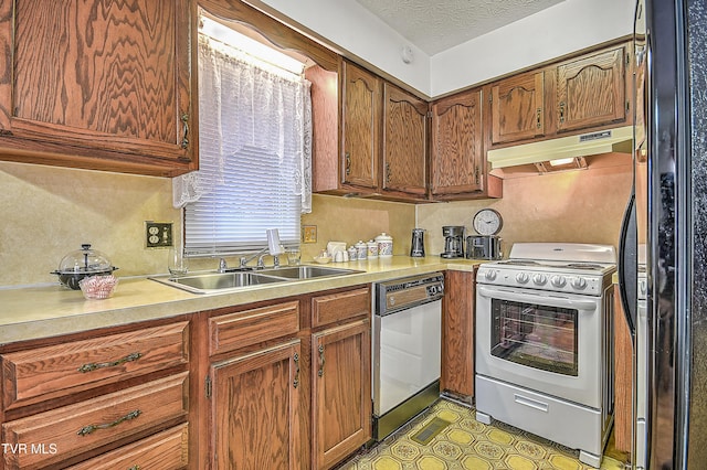 kitchen with black refrigerator, sink, a textured ceiling, and white range with electric stovetop