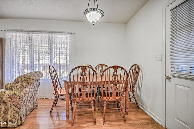 dining space with light hardwood / wood-style floors and a textured ceiling