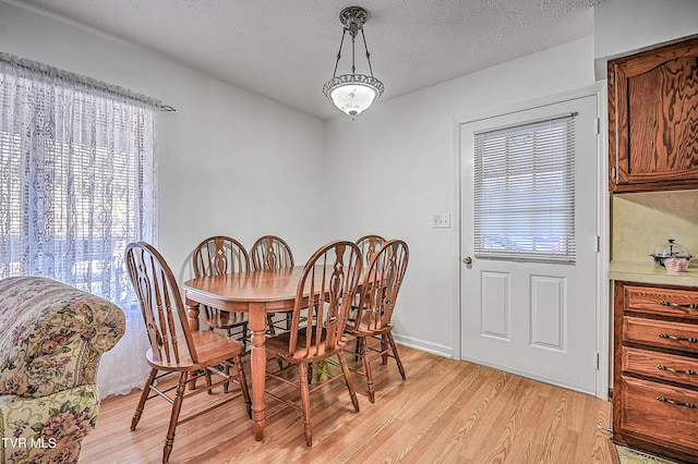 dining area featuring light hardwood / wood-style flooring and a textured ceiling