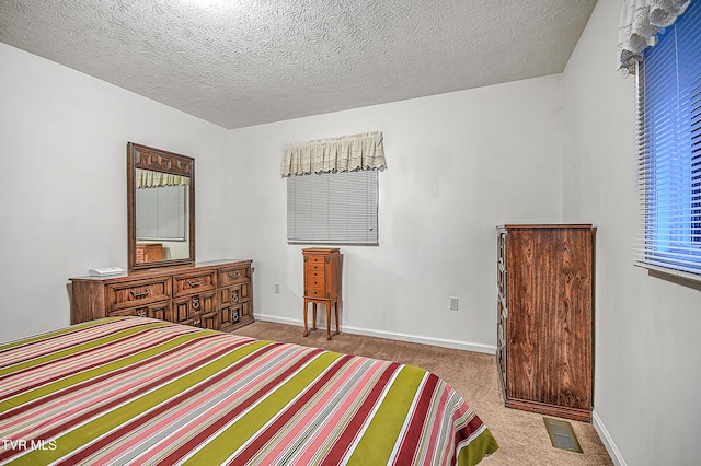 bedroom with light colored carpet and a textured ceiling