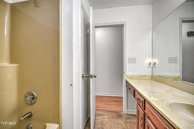 bathroom with vanity, bathing tub / shower combination, and a textured ceiling