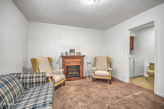 living area featuring carpet, a textured ceiling, and washer and clothes dryer