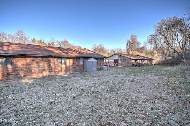 exterior space featuring a carport, a storage unit, a yard, and central air condition unit