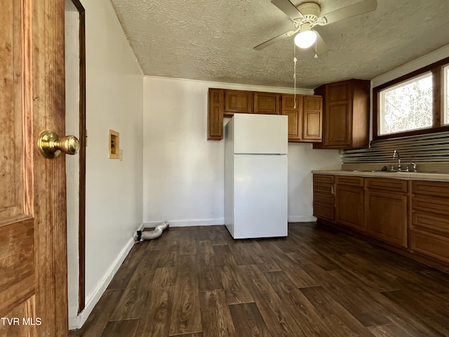 kitchen featuring sink, ceiling fan, white refrigerator, a textured ceiling, and dark hardwood / wood-style flooring