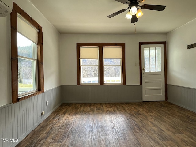 empty room featuring dark hardwood / wood-style floors, a wall mounted air conditioner, and ceiling fan