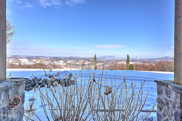 yard layered in snow featuring a mountain view